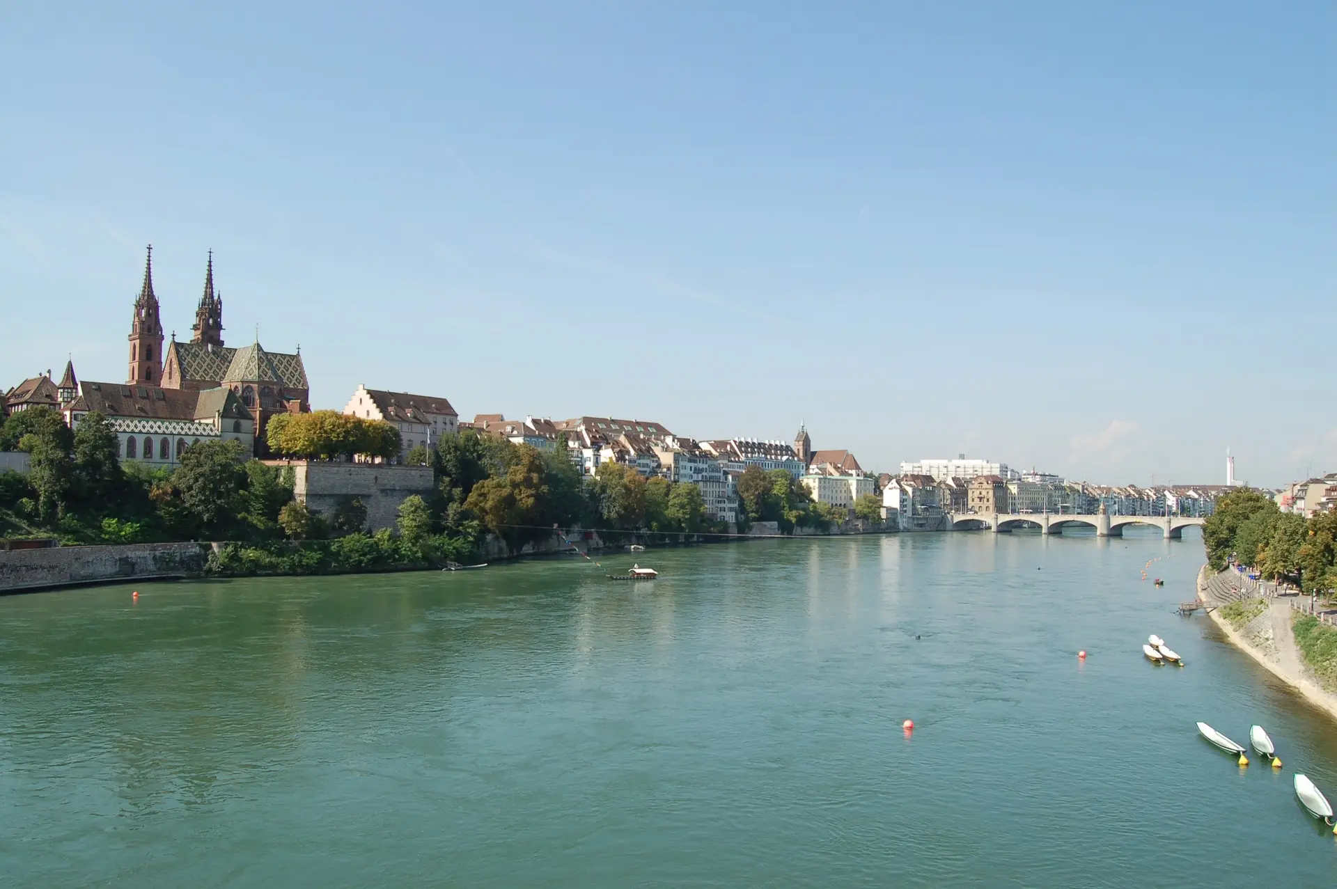 Couple on a wooden Rhine ferry in Basel with the red sandstone Münster on the hill behind