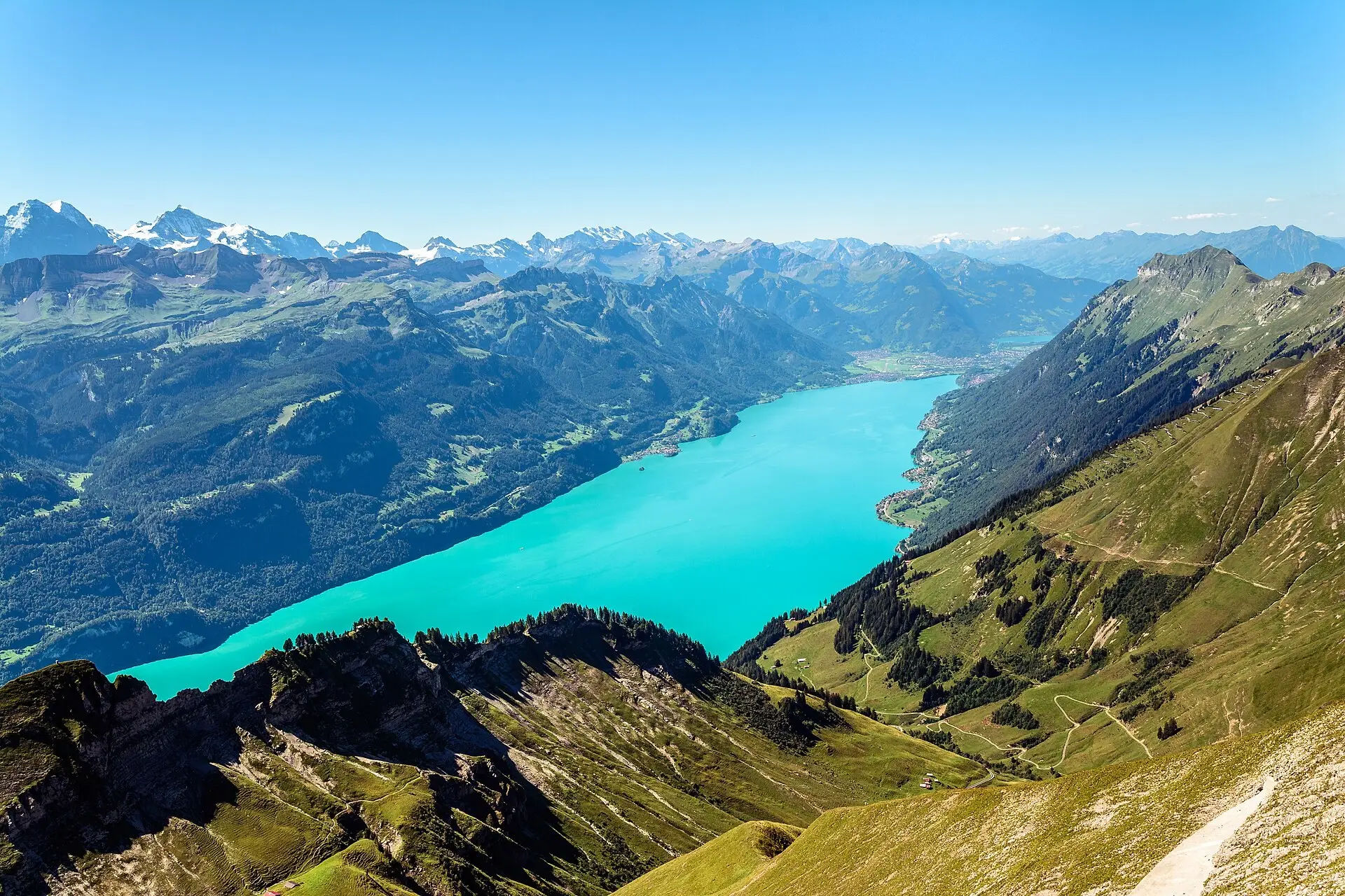Couple on the lakeside promenade in Brienz with turquoise Lake Brienz and wooded mountains behind