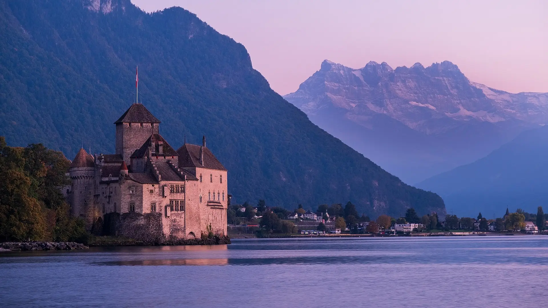 Chillon Castle on its rock in Lake Geneva at golden hour, with the Dents du Midi rising behind it