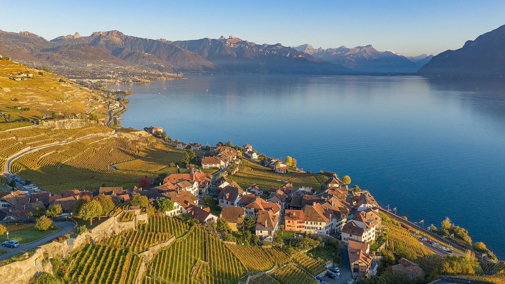A bride and groom on a boat dock on Lake Geneva at golden hour, vineyards rising behind them