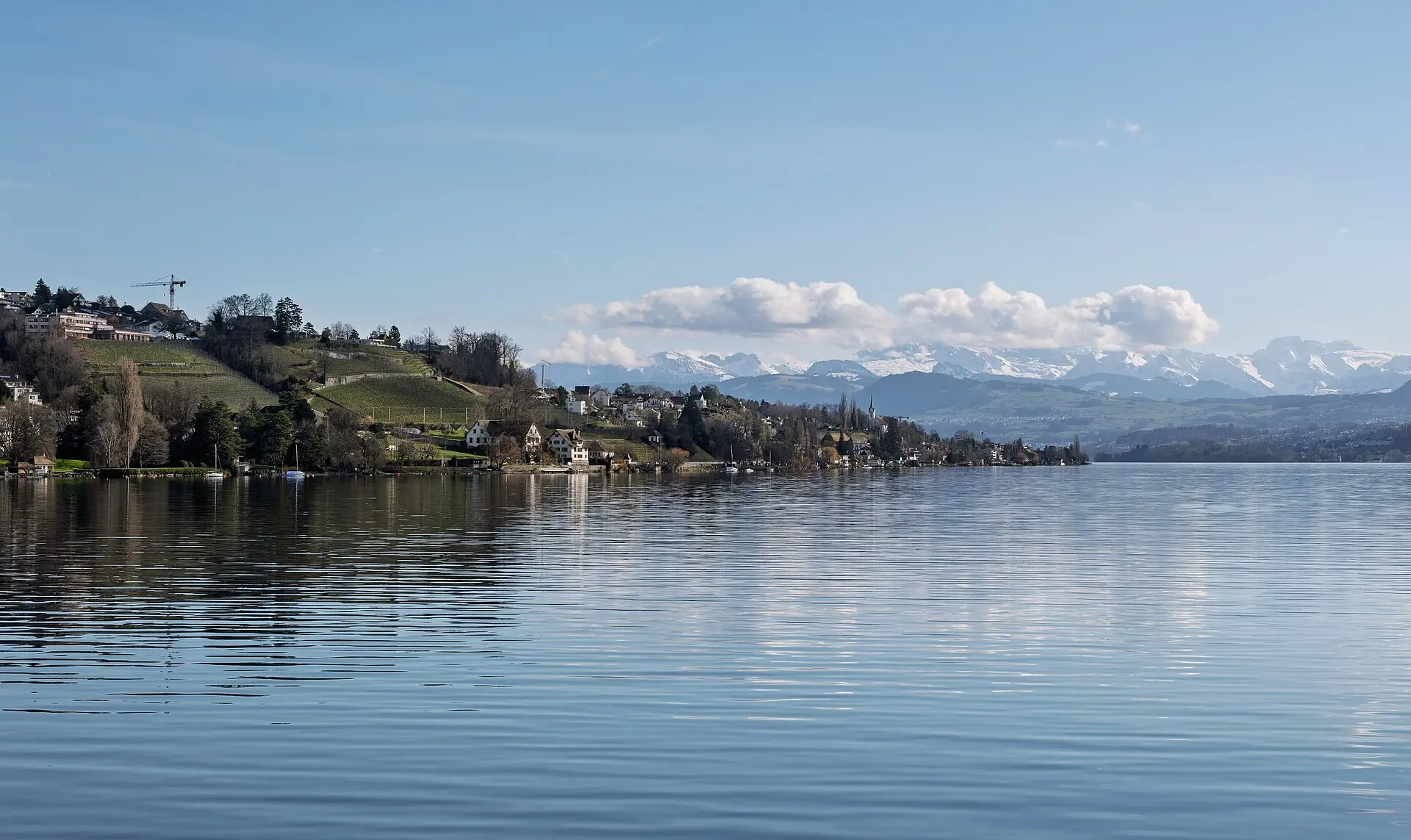 Couple walking on the long wooden footbridge between Rapperswil and Hurden across Lake Zurich at sunset
