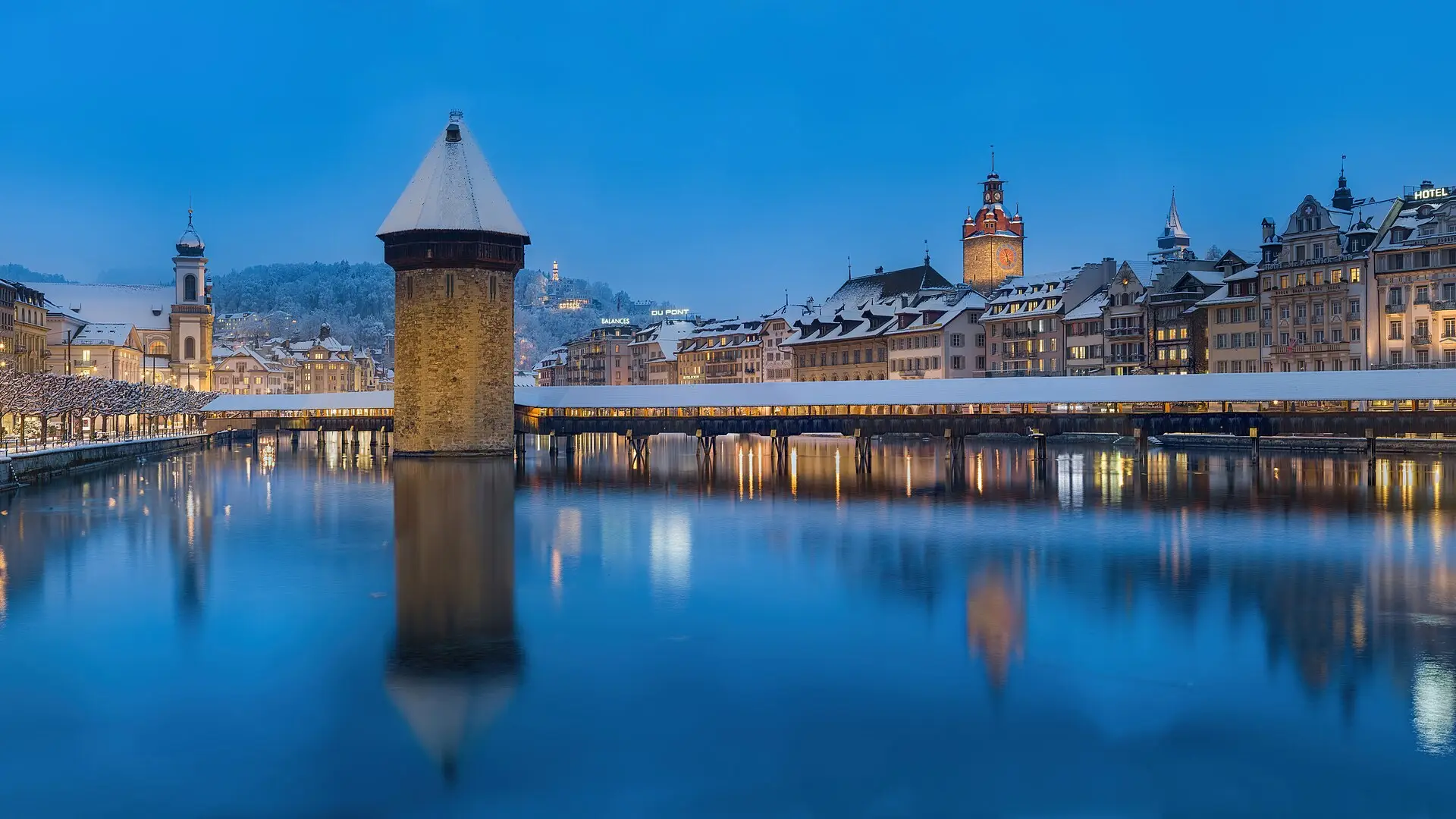 A couple walking arm in arm along a lakeside promenade in Switzerland in soft evening light