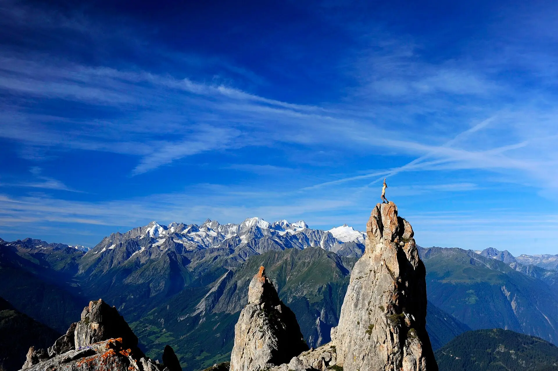 A couple on a mountain ridge above Verbier at sunset, the Val de Bagnes and the Grand Combin behind them